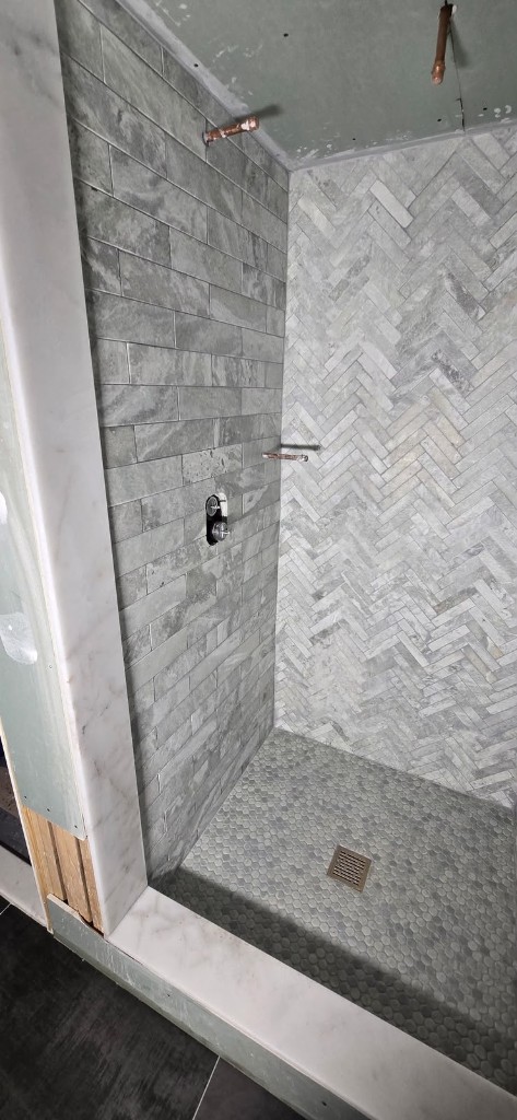Stone tile shower with herringbone pattern