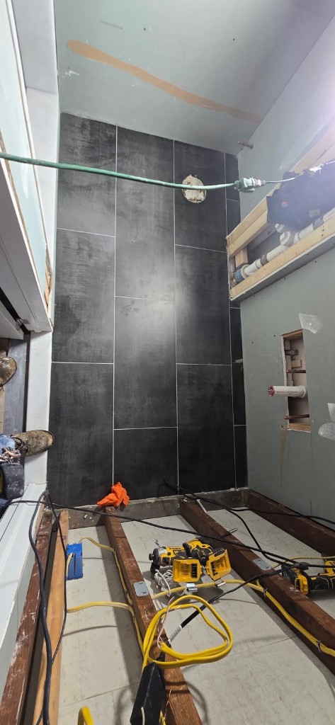 Charcoal floor tile install with drywall and plumbing rough-in