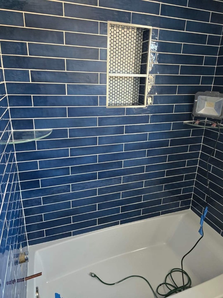 Navy subway tile tub surround with penny tile niche