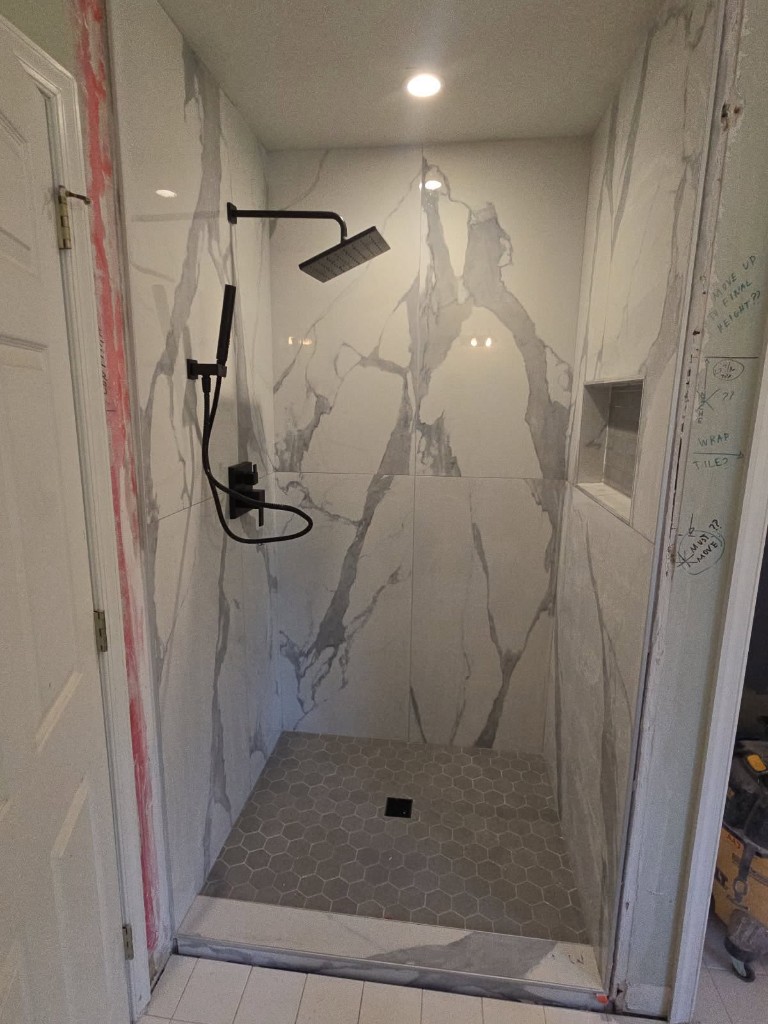 Walk-in shower with marble-look tile and matte black fixtures