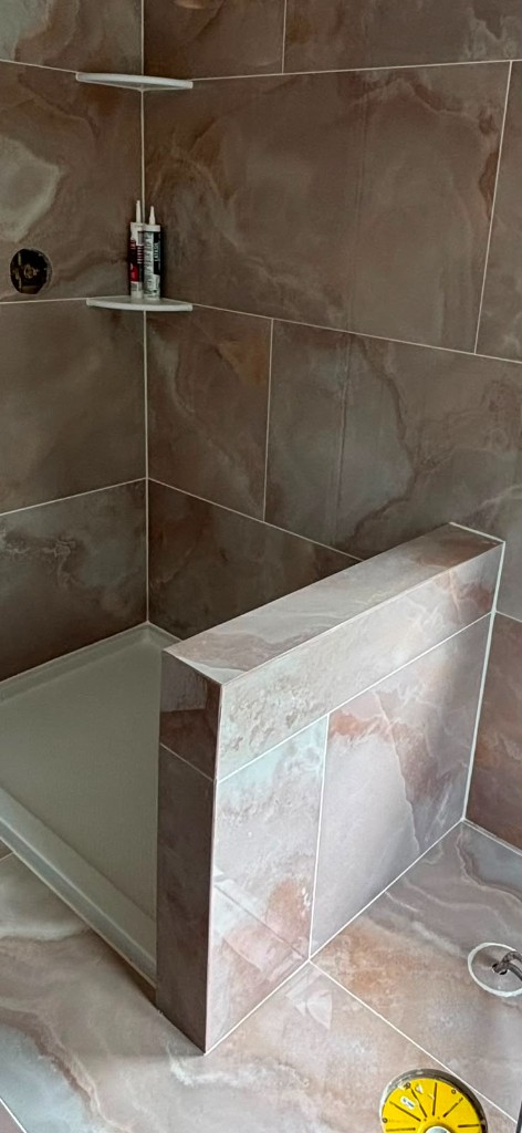 Porcelain-look tile shower with pony wall and white pan